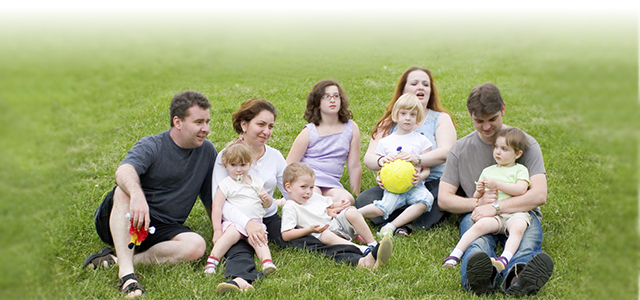 Image of adults and children sitting on grass.